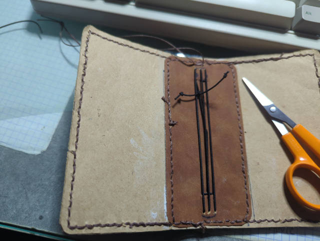 Photo:Intérieur de la couverture en faux cuir. Les bords sont cousus, ainsi que le renfort central